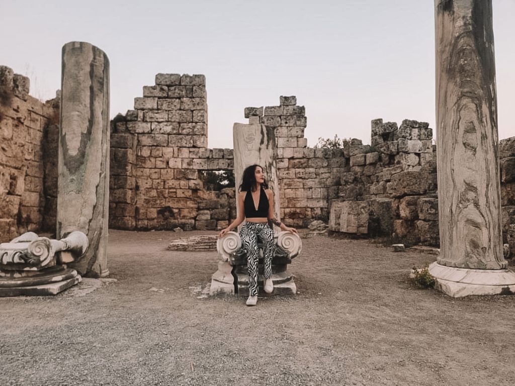 Girl sitting on an ancient throne. At perge ancient city.